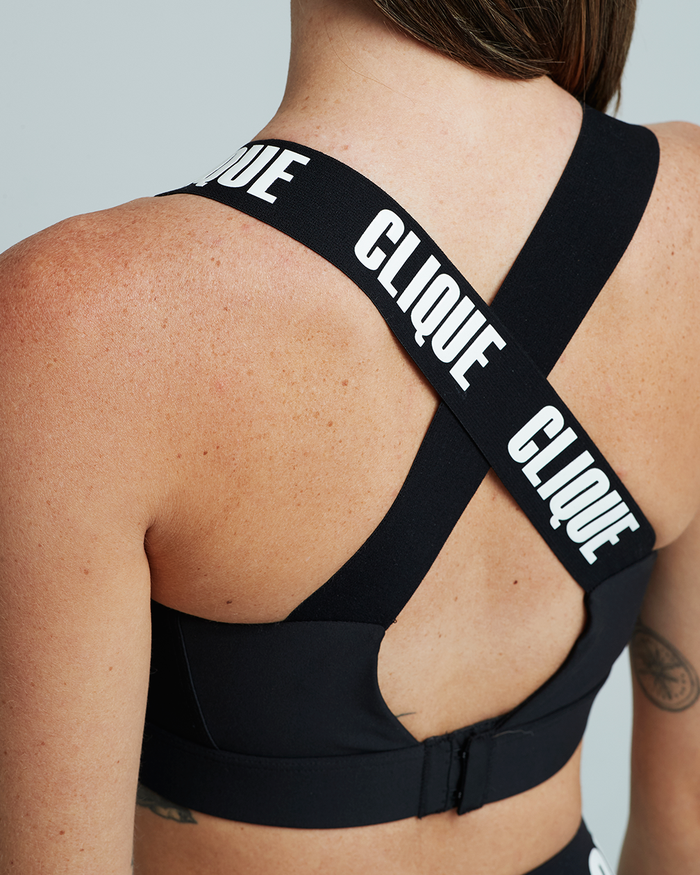 Close up rear view of model wearing super support bra in black with clique written on crossover straps